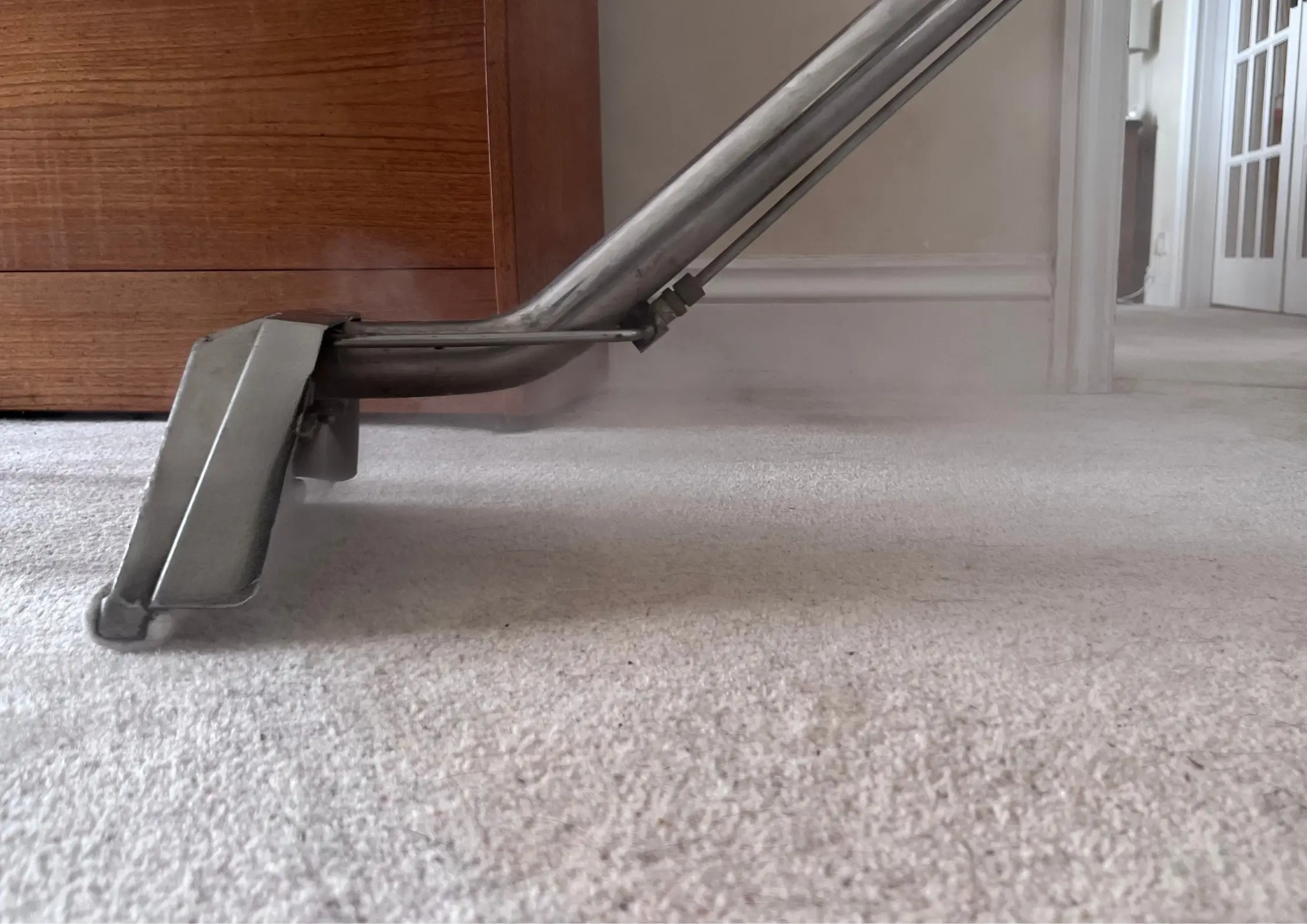 Close-up of an industrial extraction wand flushing deep-seated grit and bacteria from a school carpet runner.